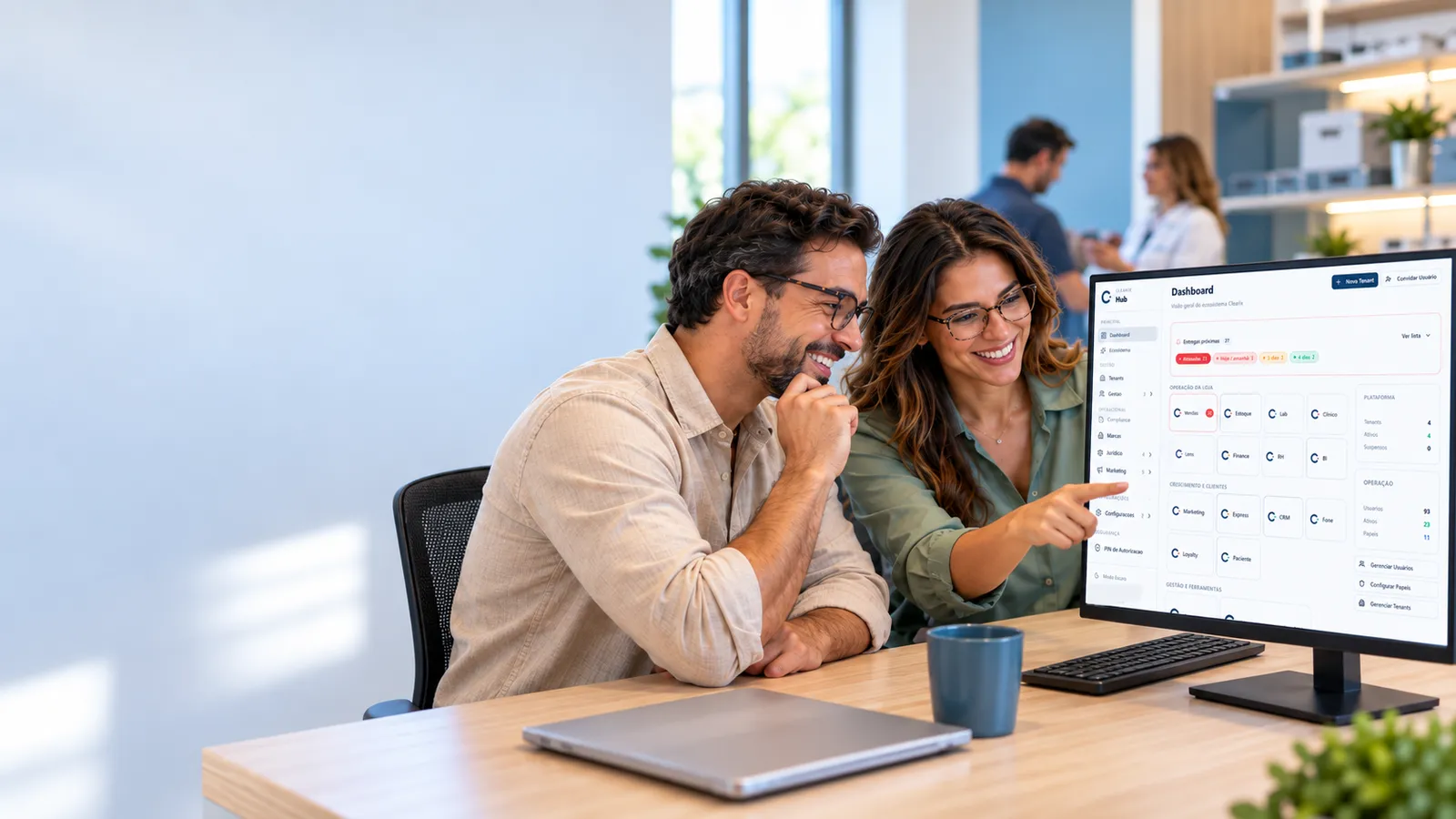 Duas pessoas da equipe de uma ótica sorrindo e apontando para o monitor de um PC que mostra o painel do Clearix Hub